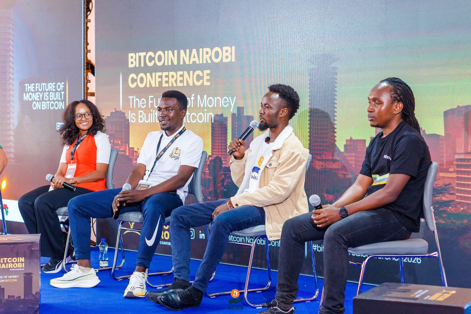 Bitika on a panel at the Bitcoin Nairobi Conference, under a screen reading 'The future of money is built on Bitcoin'